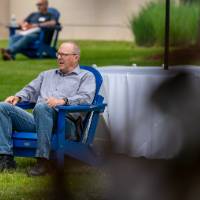 A gentleman and woman sitting in blue lawn chairs outside